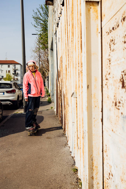 Young diverse rebel alternative queer woman skating riding longboard outdoor - Фото, изображение