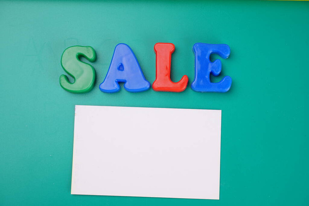 "Πώληση" λέξη και λευκό κενό χαρτί σε πράσινο φόντο - Φωτογραφία, εικόνα