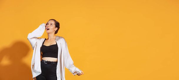 Portrait of young emotive woman in casual clothes posing with shocked expression isolated over yellow studio background. News. Concept of beauty, lifestyle, youth, emotions, facial expression, ad - Foto, immagini