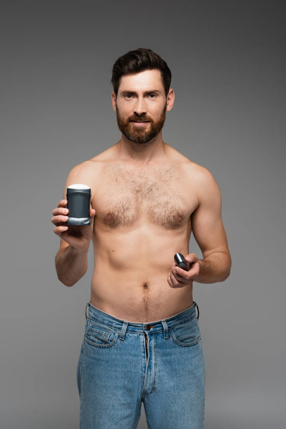 shirtless man with beard holding deodorant isolated on grey - Foto, afbeelding