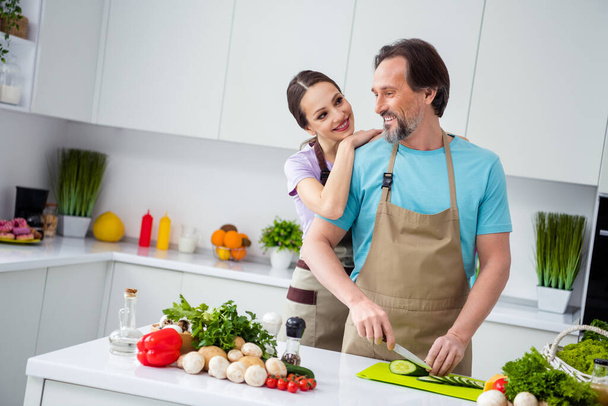 Portrait of cheerful idyllic people embrace prepare chop fresh vegetables weekend kitchen indoors. - Foto, imagen