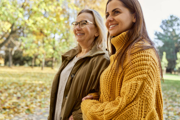 Senior woman with her adult daughter walking at the park during the autumn  - Foto, Imagem