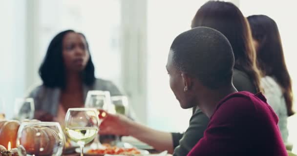 Black family enjoying thanksgiving meal together looking happy, smiling and drinking white wine at home. Relaxed, carefree and friendly group eating lunch at a dinner table during a social gathering. - Video