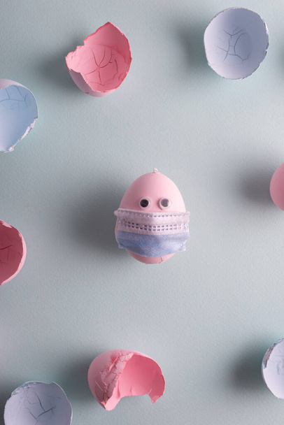 egg in a protective medical mask. Coronavirus Easter in pastel colors. Pink blue holiday quarantine concept. - Фото, изображение