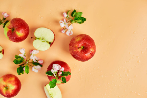 Tranché, pomme rouge entière et fleurs un plat posé sur un fond orange pastel, Fruits et fleurs, concept sping. Vue du dessus - Photo, image