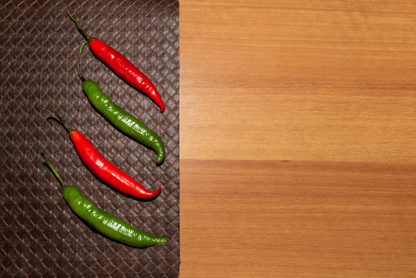 Peppers over a brown placemat on a wooden table. Background with copy space. - Foto, Bild