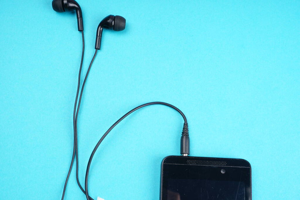 Smartphone with headphones on turquoise background - Foto, Imagen