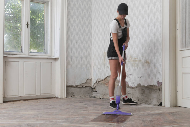Woman mopping the very dusty wooden floor during house renovation - 写真・画像