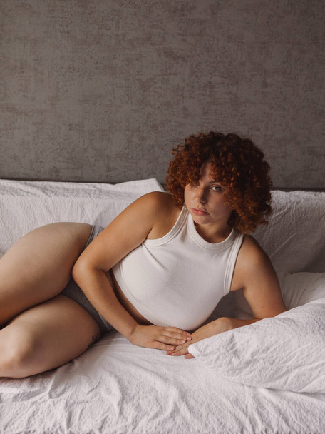 Beautiful girl with curly red hair on the bed in the morning  - Fotografie, Obrázek
