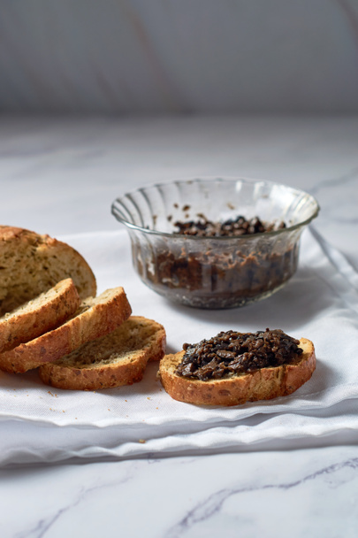 Black Olive Tapenade in bowl with spoon and Bread. - Photo, image