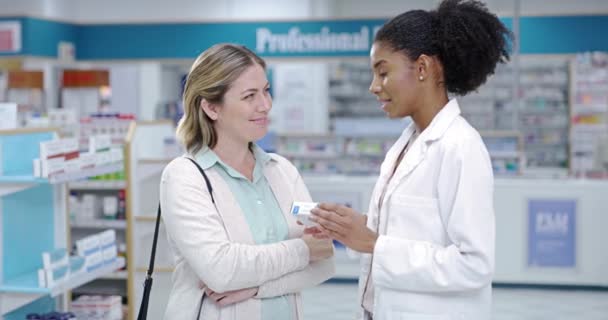 A young pharmacist explaining medical treatment to a woman in a modern drugstore. Guiding, assisting with the best health care advice and option. Worker providing great customer service at a pharmacy. - Filmati, video