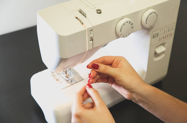 Woman is putting thread in sewing machine. Girls hands at freelance work. Fashion concept. Creating of new clothes process. Hobby ideas. - Фото, зображення