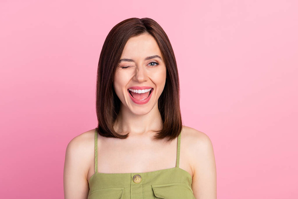 Photo of nice adorable gorgeous woman with bob hairstyle wear khaki tank blinking at camera to you isolated on pink color background. - Photo, image