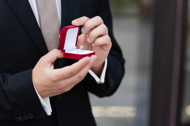 Περικοπή άποψη του ανθρώπου σε κουτί εκμετάλλευση κοστούμι με δαχτυλίδι εμπλοκής σε εξωτερικούς χώρους  - Φωτογραφία, εικόνα
