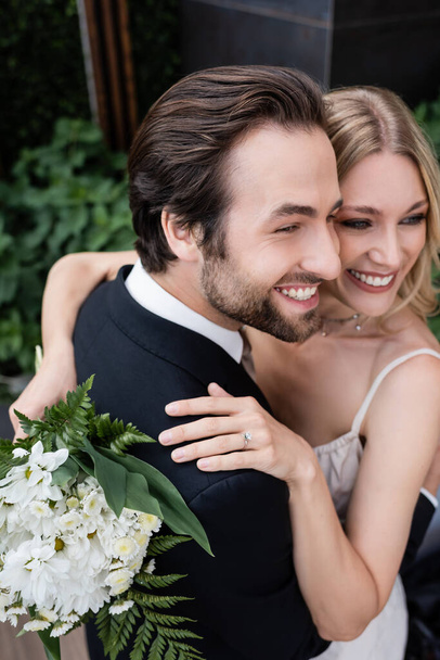 High angle view of newlyweds with flowers embracing outdoors  - Photo, image