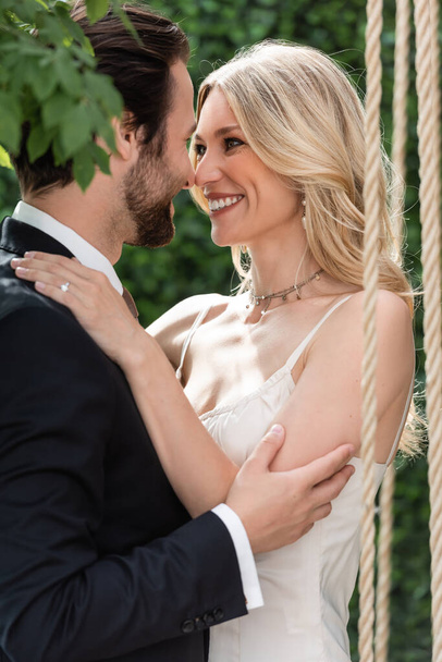 Positive newlyweds smiling and hugging outdoors  - Fotó, kép