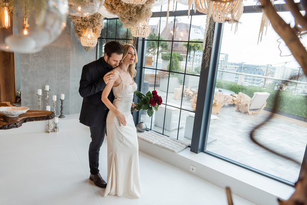 Man in suit touching elegant girlfriend in dress with roses in restaurant  - Valokuva, kuva