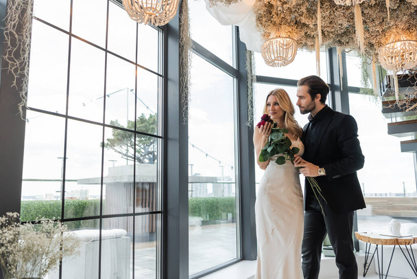 Elegant couple holding roses during date in restaurant  - Foto, Imagen