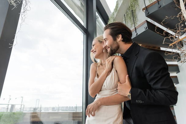 Side view of cheerful romantic couple looking at window in restaurant  - Photo, Image