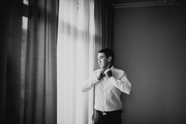 Grooms morning preparation. Handsome man getting dressed and preparing for the wedding. - Photo, image