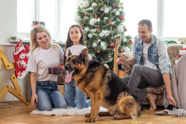 Kerst Familie Portret In Home Vakantie Woonkamer, Kid and dog play, Cadeau Box aanwezig, Huis verfraaien door kerstboom. - Foto, afbeelding