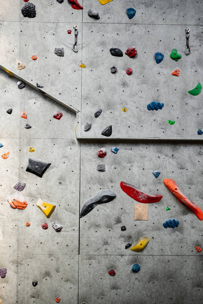 Close up photo of a rock climbing wall with climbing holds in gym.  - Foto, Bild