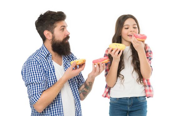 Sharing donuts for two. Bearded man and little girl holding ring donuts. Father and small daughter child eating tasty glazed donuts. Hipster and adorable kid with fried donuts in hands. - Foto, immagini
