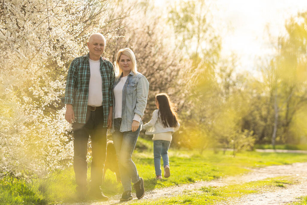 grandfather with granddaughter and daughter in spring, senior man in the yard. - Fotografie, Obrázek