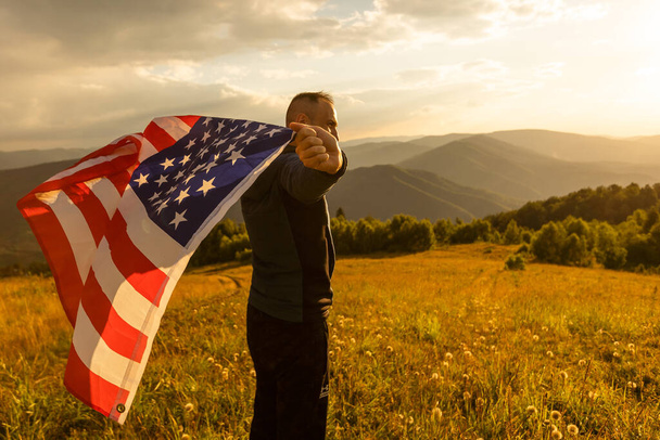 Young man proudly waving the American flag at sunset. - 写真・画像