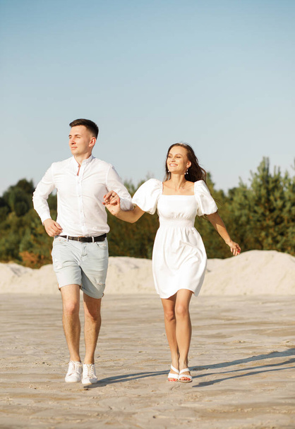 Весела пара біжить на піску тримаючи руки
. - Фото, зображення