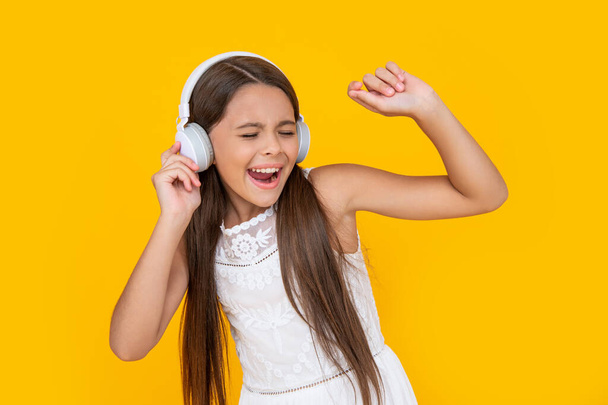 singing teen kid listen music in headphones on yellow background. - Foto, Imagen