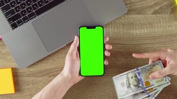 Guy is showing how easy to earn money with freelance green screen mockup chroma key. Waving american dollars. - Video, Çekim