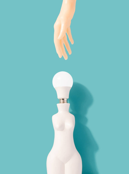 Female shaped vase with light bulb instead of a head with hand reaching. Electricity, power minimal concept. - Фото, изображение