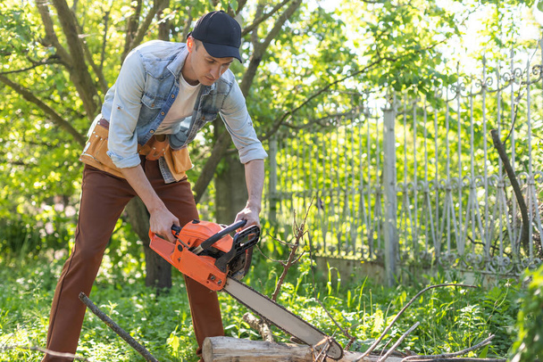 Człowiek z piłą łańcuchową. usuwa sadzenia w ogrodzie ze starych drzew, zbiera drewno opałowe - Zdjęcie, obraz