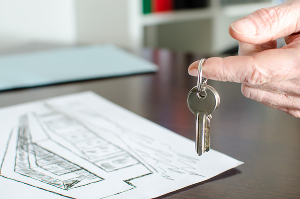 Агент по недвижимости показывает ключи от дома
 - Фото, изображение