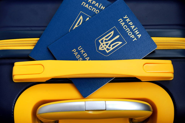 2 passports of citizens of Ukraine lie on yellow blue suitcase in color of Ukrainian flag at border. Travel concept, refugees, tourism, emigration - Foto, Bild