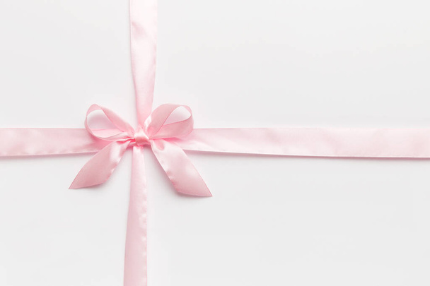 Top view of purple ribbon rolled and pink bow isolated on colored background. Flat lay with copy space. - Photo, image