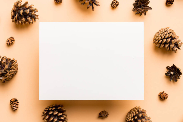 Marco creativo hecho de conos de pino de Navidad con papel cuadrado en blanco. Tema Navidad y Año Nuevo. Colocación plana, vista superior espacio de copia. - Foto, Imagen