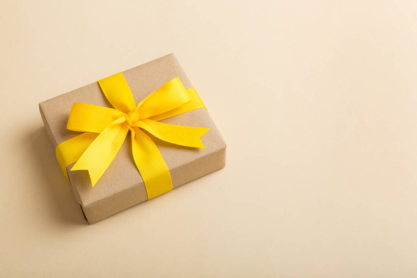 Verhüllte Weihnachten oder andere Feiertage handgemachtes Geschenk in Bastelpapier mit farbigem Band. Geschenkschachtel, Geschenkdekoration auf dem Tisch, Draufsicht mit Kopierraum. - Foto, Bild