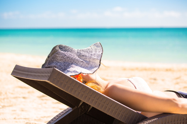 mujer con sombrero de sol disfrutando de la vista al mar sentada en la silla de una playa
 - Foto, Imagen
