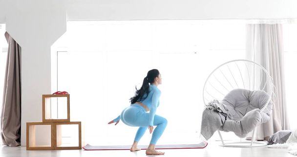 Athletic fit girl doing fitness aerobic exercises in living room. Home fitness and wellness concept. - Foto, imagen