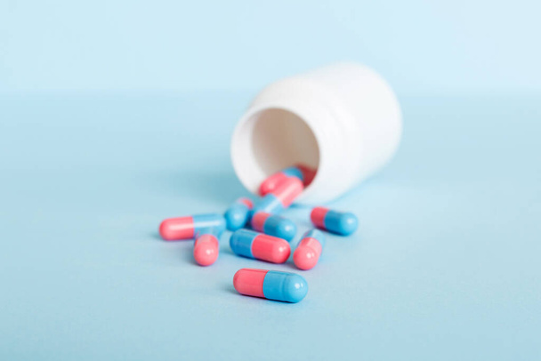 plastic medicine bottle with capsules of pills on colored background. Online pharmacy. Painkiller medicine and antibiotic drug resistance concept. Pharmaceutical industry. - Фото, зображення
