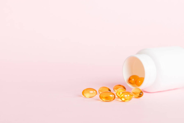 Soft gels pills with Omega-3 oil spilling out of pill bottle close-up. Gel capsules bottle white surface. Omega 3, multivitamins, Calcium, antibiotics. Health. Immunity. - Fotó, kép
