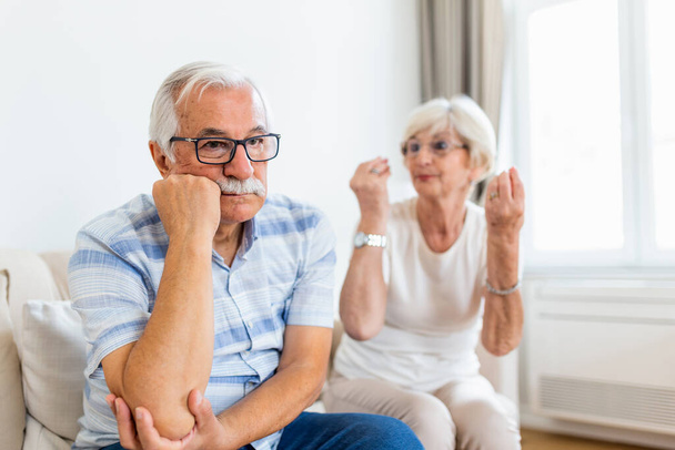 Senior couple arguing. Elderly woman frustrated with her husband. Older couple sitting on the sofa at home,having fight. Marriage issues, pre-divorce period - Photo, Image