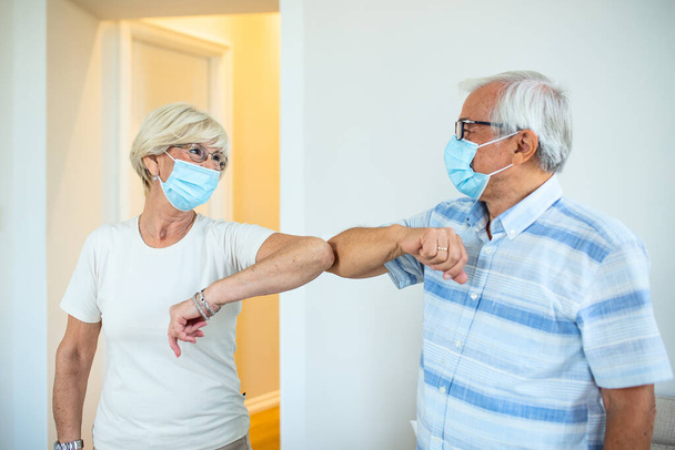 Friendly smiling senior friends keeping social distance, greeting each other by bumping elbows instead of hugs or handshaking, preventing covid 19 coronavirus infection spread. - Foto, imagen
