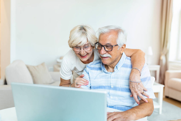 Elderly spouses at home. Wife hugs husband.Having pleasant conversation chatting with grown up children and grandchildren using wireless tech concept - Photo, Image