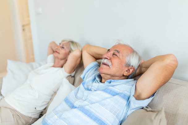 Close up of peaceful aged couple lying with eyes closed relaxing on cozy sofa, calm senior husband and wife nap on couch at home seeing dreams, elderly man and woman rest spending weekend indoors - 写真・画像