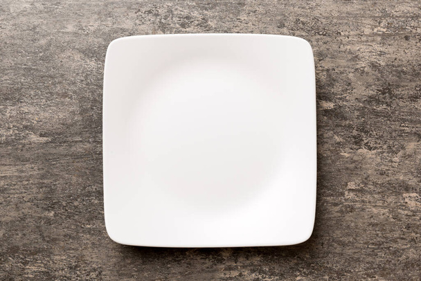 Top view of empty square plate on cement background. Empty space for your design. - Foto, afbeelding