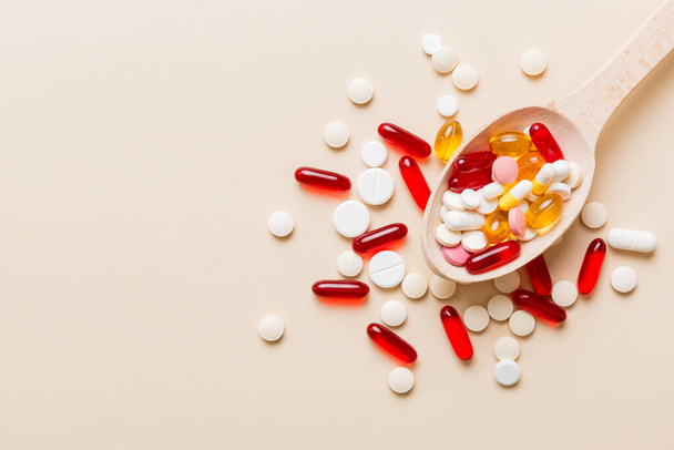 Vitamin capsules in a spoon on a colored background. Pills served as a healthy meal. Red soft gel vitamin supplement capsules on spoon. - Photo, Image
