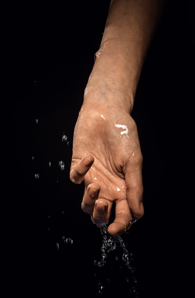 A wet hand on a black background - 写真・画像